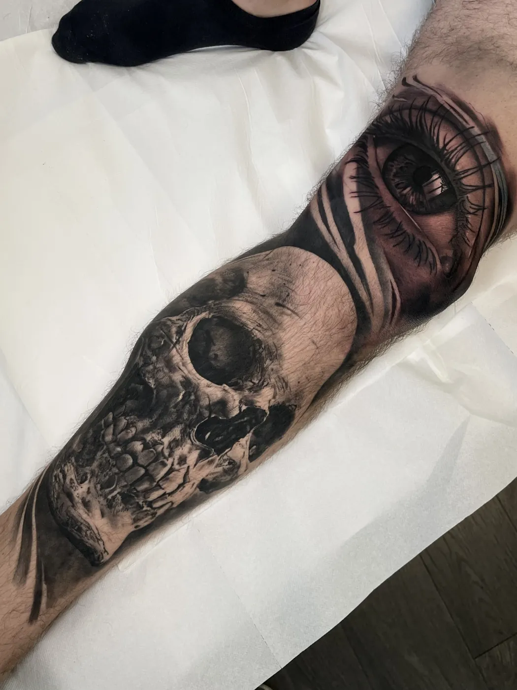 Black and grey skull and eye forearm tattoo